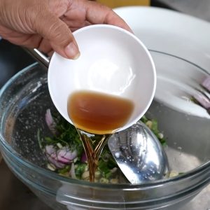 a person pouring a liquid into a bowl of food