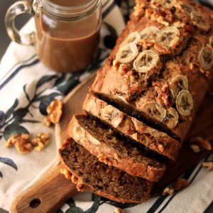 a loaf of banana nut bread sitting on top of a wooden cutting board