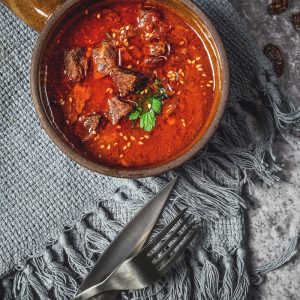 skewed meat in bowl beside knife and fork