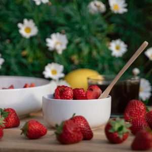 strawberries and yellow flowers in white ceramic bowl