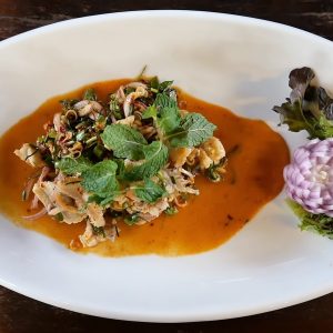 a white plate topped with a salad covered in sauce