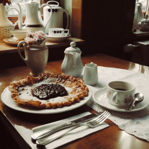 pie on plate beside knife, fork, and mug