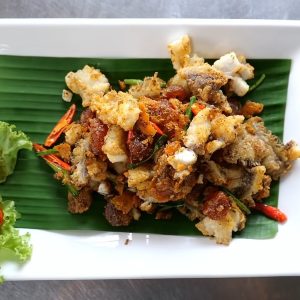 a white plate topped with fried food next to a green leaf