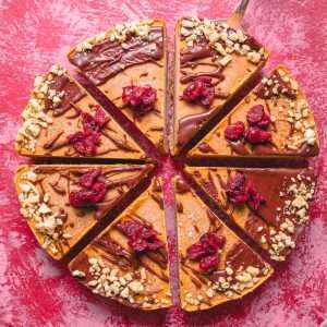 a cake with chocolate and nuts on a pink surface