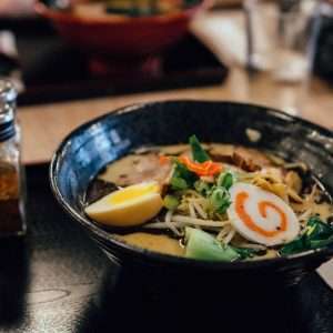 focus photography of ramen in bowl with condiment shakers