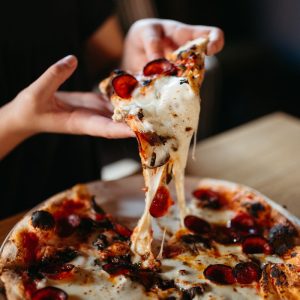 a person takes a slice of pizza