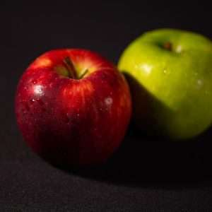 a green and a red apple on a black background