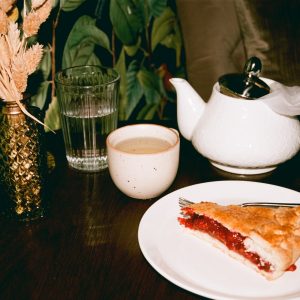 a piece of pie on a plate next to a cup of tea