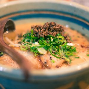 a bowl of soup with meat and broccoli on a plate