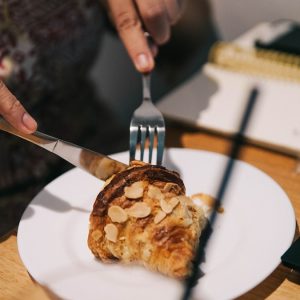 person holding stainless steel fork and white ceramic plate