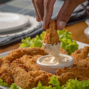 person dipping fried cuisine on dip