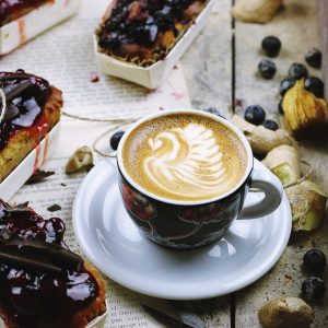 photo of brown and white teacup filled with coffee on saucer