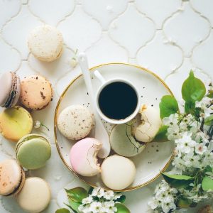 macarons beside teacup and ladle on round white ceramic plate