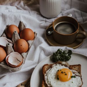 three eggs on white ceramic plate beside brown ceramic mug