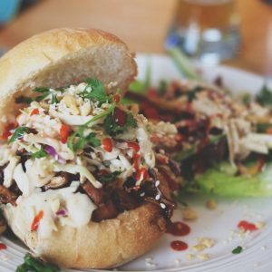 patty with coleslaw and ham on white plate