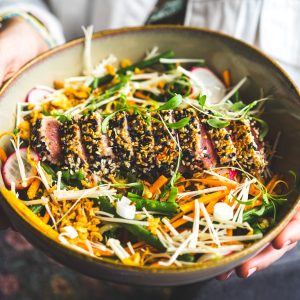 person holding black ceramic bowl with vegetable salad