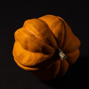 a small orange pumpkin sitting on a black surface