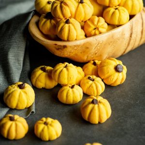 a wooden bowl filled with yellow mini pumpkins