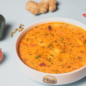 a bowl of soup next to some vegetables