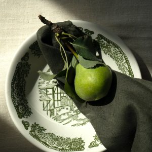 a green apple sitting on top of a white plate