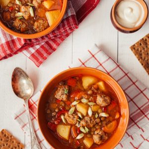 two bowls of soup on a table with crackers