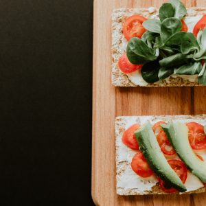 bread with vegetables, sliced tomatoes and spread filling on brown wooden board