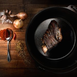 a steak is cooking in a skillet on a wooden table