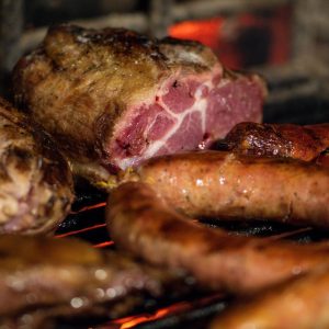 a close up of meat and sausages cooking on a grill