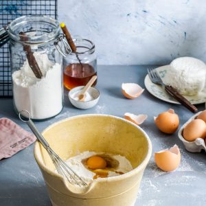 brown mixing bowl with eggs and flour with whisk
