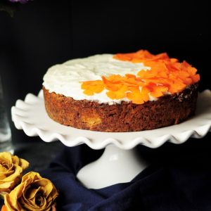 white and orange icing-coated cake on scalloped edge white ceramic cake stand
