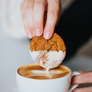 person holding white ceramic mug with brown and white liquid