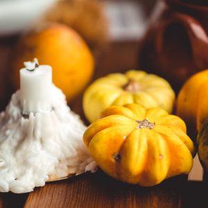 white candle near pumpkins