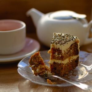 white and brown cake on white ceramic saucer beside pink ceramic teacup