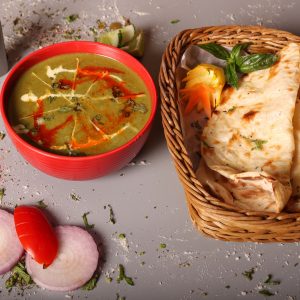 a bowl of soup next to a basket of pita bread