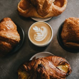 coffee surrounded by four baked breads