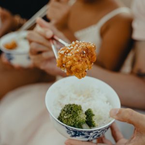 woman in white tank top holding spoon with rice