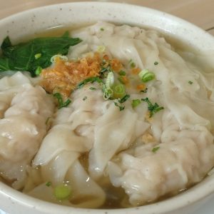 a white bowl filled with dumplings on top of a wooden table