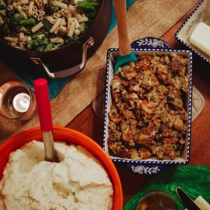 a table topped with plates of food and a bowl of mashed potatoes