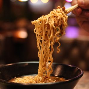 a hand holding a stick over a bowl of food