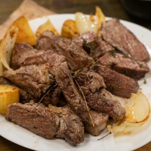 a white plate topped with meat and potatoes